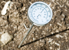 thermometer in compost reads 140 degrees F; photo by Edwin Remsberg, USDA