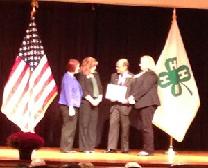 Eddie receiving his induction certificate. (left to right) Dr. Lisa Lauxman, Director, Division of Youth and 4-H, NIFA, USDA; Kimberly Gressley, NAE4-HA Past-President; Eddie; Caroline Fernandez, Office of the President and CEO, National 4-H Council.