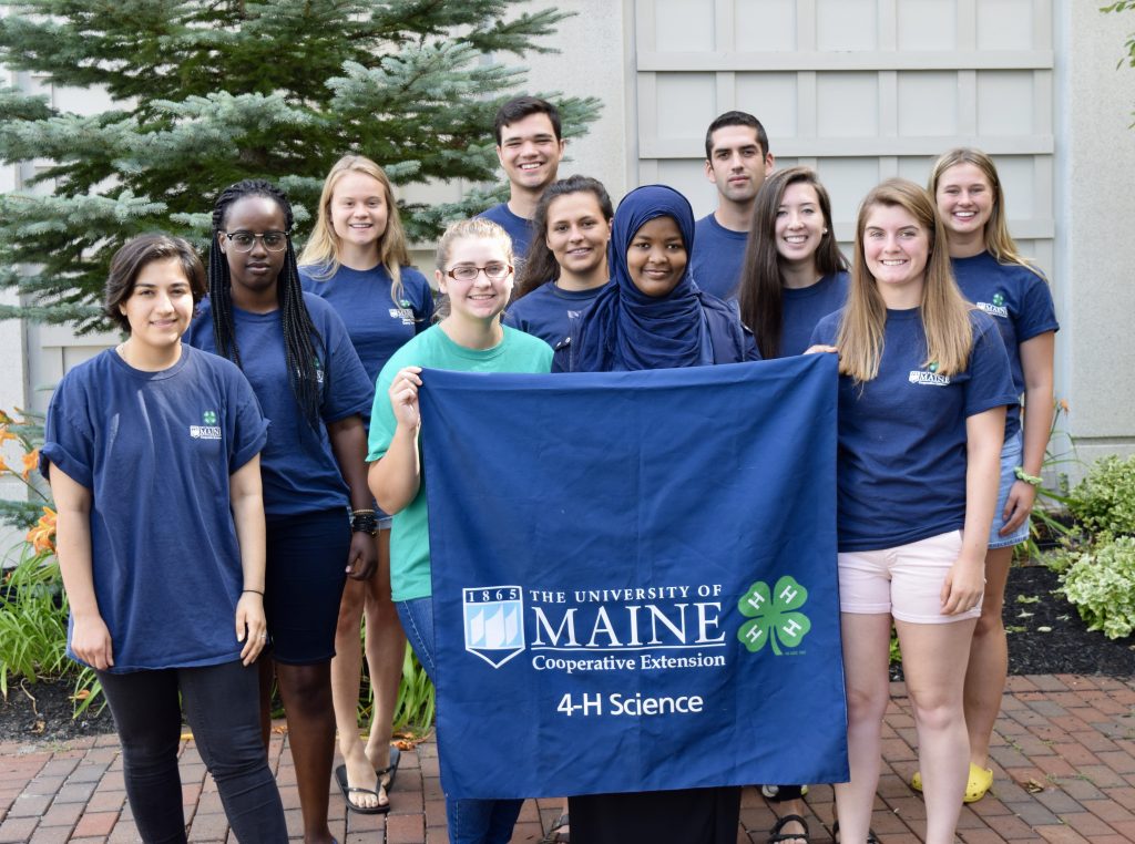 Summer of Science interns holding 4-H science banner