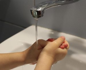 washing hands under a faucet with running water
