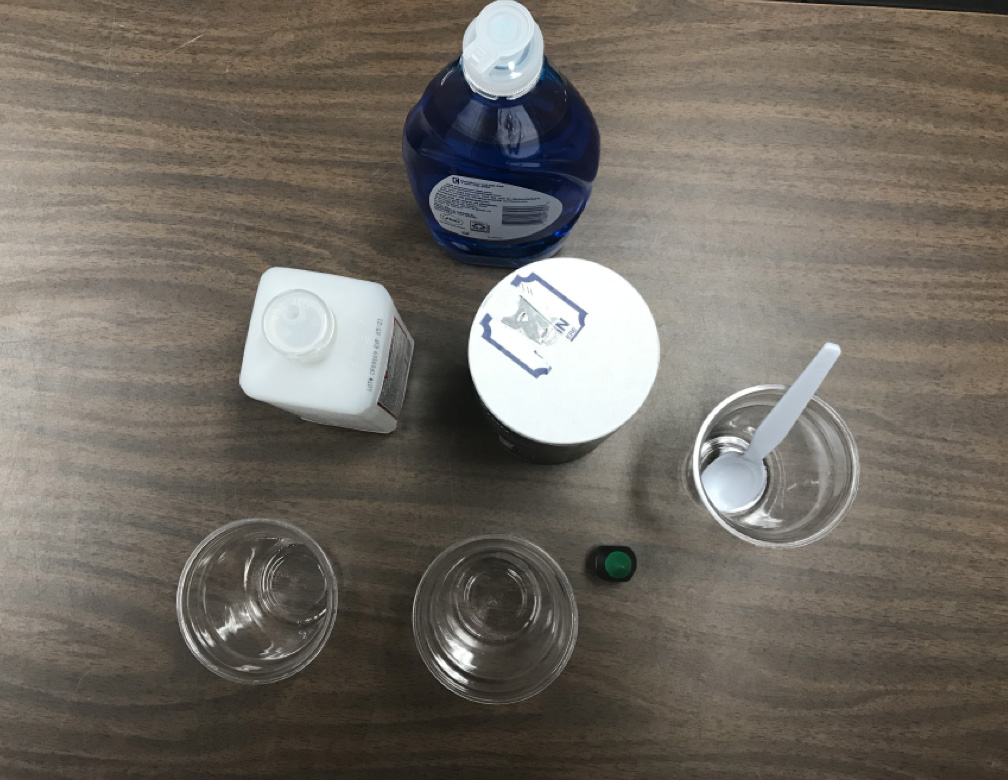 DNA kit setup: dishwashing liquid, salt, isopropyl alcohol, plastic cups, food color, spoon