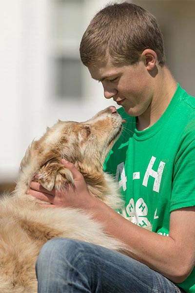 a teen boy wearing a 4-H t-shirt with a dog
