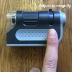 pocket microscope shown with a persons finger indicating where to adjust to magnify