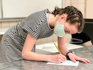 teenager leaning over a table filling in a form before speaking at the 4-H Public Speaking event, 2022