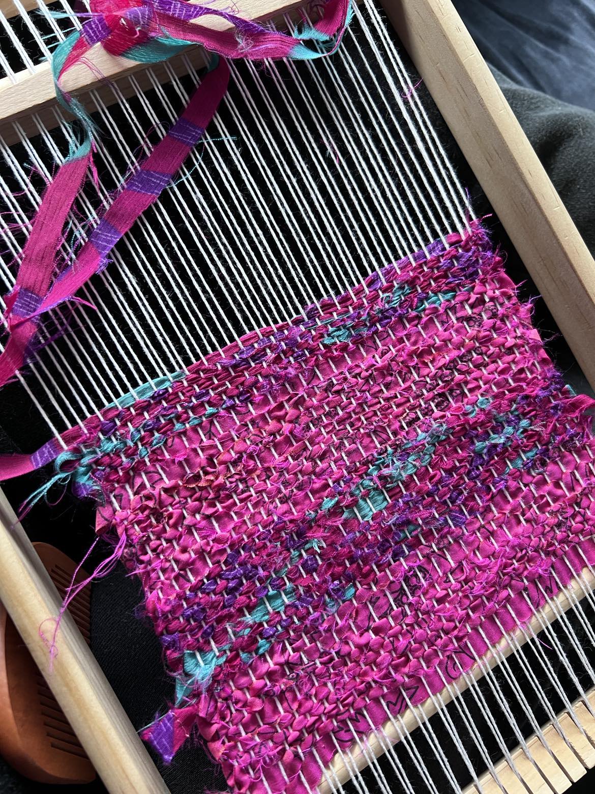 In-Process tapestry being woven on a small hand-loom. Pinks and Turquoise textiles.