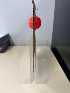 Red plastic ball in a piece of cardboard seen from the side