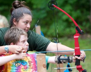 4-H member and club leader holding a bow and arrow at an archery range