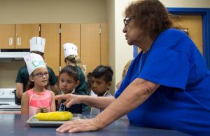 a 4-H club leader showing a group of young 4-H members how to cook