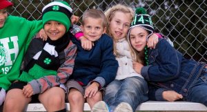 elementary school age 4-H members gathered on a bench, outside in a schoolyard