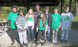 a group of pre-teen and teenage 4-H members with their club leader at an outside picnic area