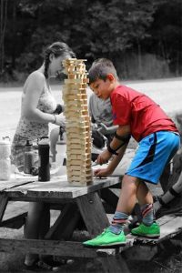boy building a wooden tile tower on a picnic table at camp