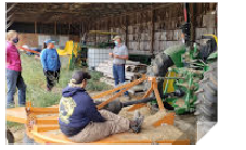 4 people gathers around a tractor implement talking