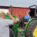man giving hand signal to woman on tractor