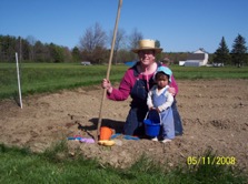Woman and child in farm clothes kneeling in a field