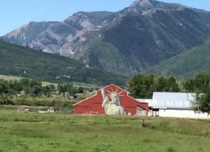 barn set in mountain valley with staue of liberty painted on it.