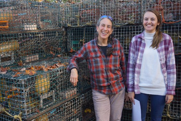 two women smiling infront of lobster traps