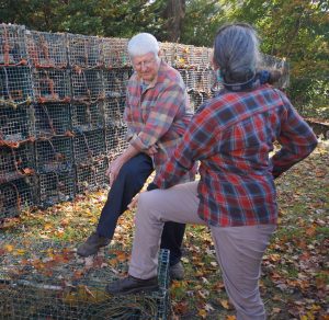 a man and a woman practicing stretches in front of stacked lobster traps