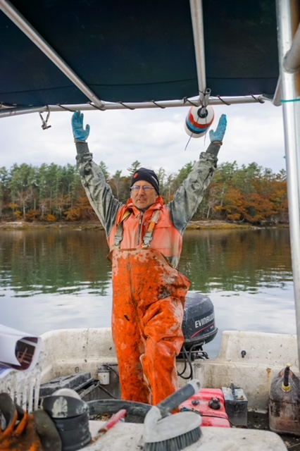 fisherman in gear on a boat, stretching with arms into the air