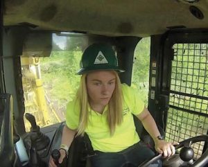 person in the cab of a large piece of-logging equipment vehicle using steering wheel