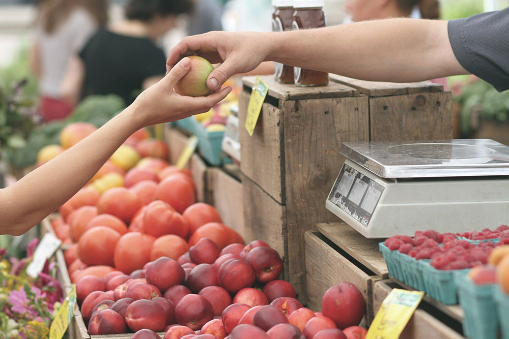 customer buying an apple at a farmers' market