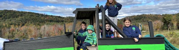 Five Midcoast Mainers members posing on a play structure that looks like a tractor