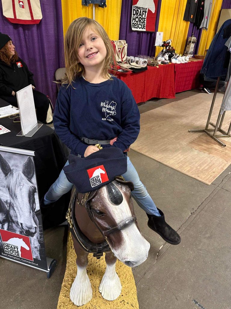 A Midcoast Mainers member sitting on a toy pony.