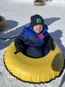 A smiling child sitting in a snow tube.
