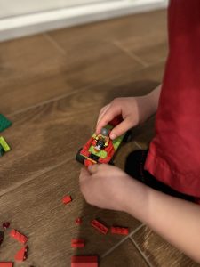 A child's hands placing a lego figure in a lego vehicle