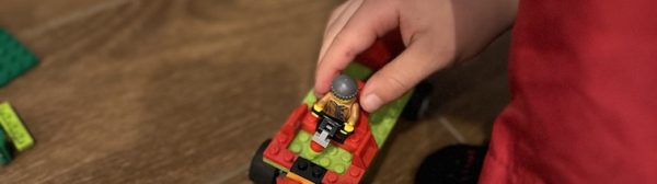 A child's hands placing a lego figure in a lego vehicle