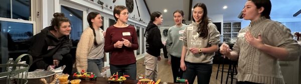 A group of teen GLEE members standing around a table with lego carts