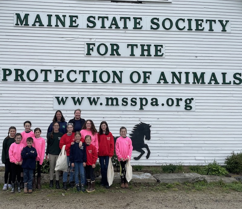 Midcoast Mainers posing in front of the Maine State Society for the Protection of Animals sign.