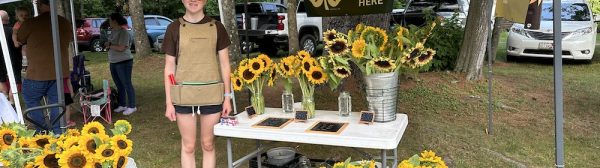 Scout standing with her sunflower stand.