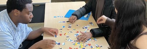 Three teen leaders doing a puzzle at a table.