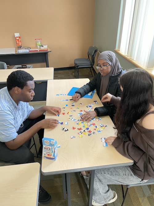 Three teen leaders doing a puzzle at a table.