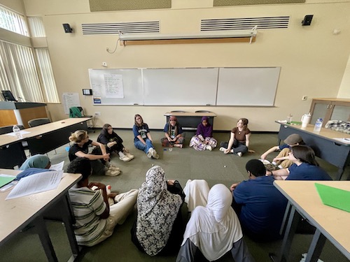 Interns and teen leaders sitting in a circle in a classroom.
