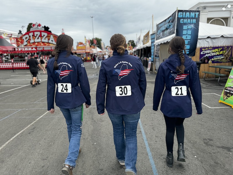 3 Midcoast Mainers walking through the Big E, wearing matching jackets.