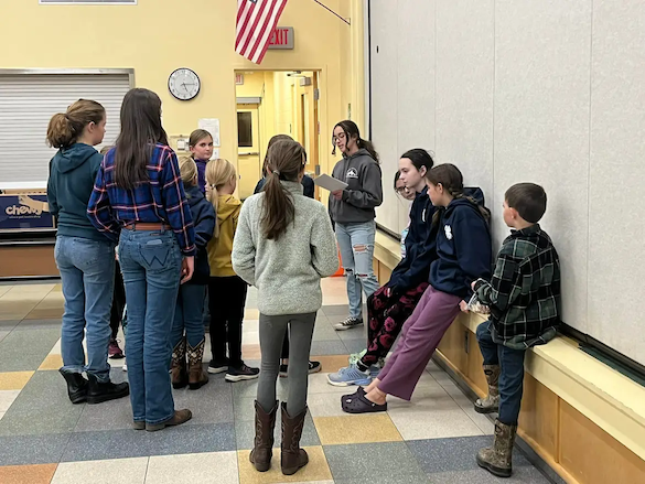 Midcoast Mainers gathered around another member reading off a piece of paper.