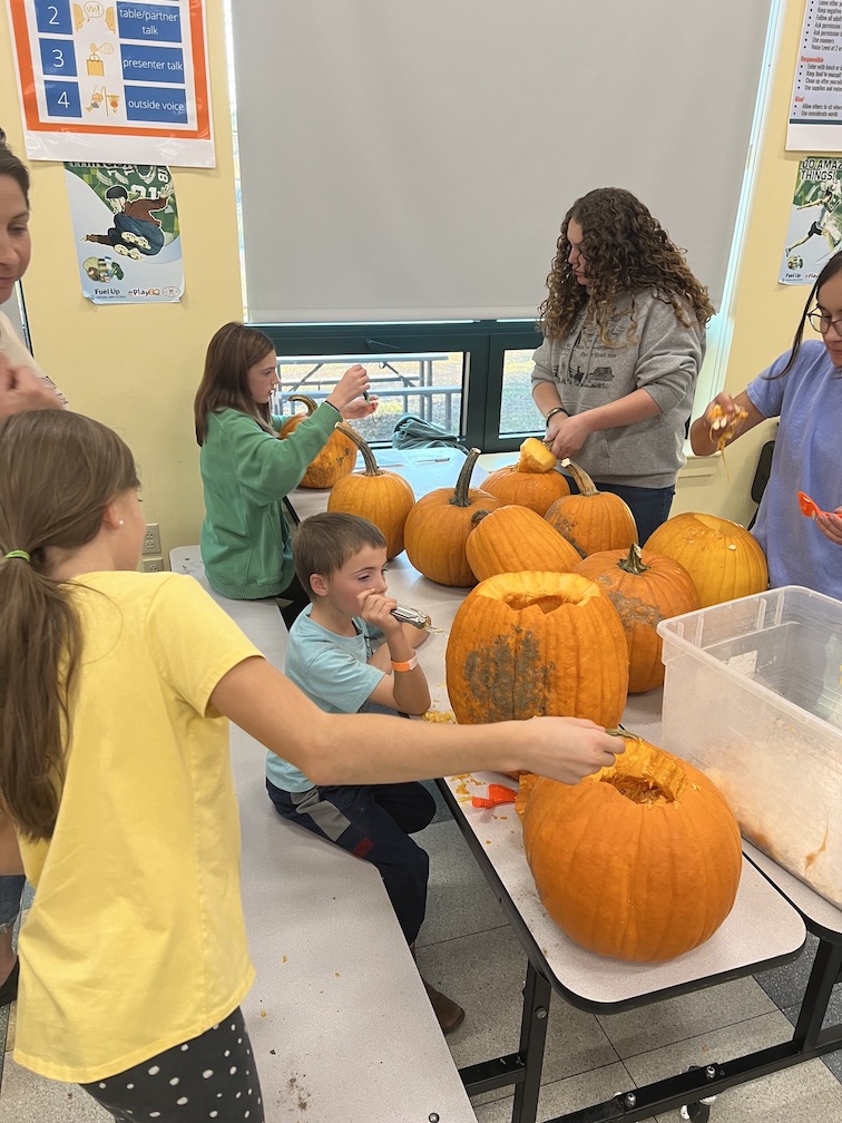 Children carving pumpkins at a table.