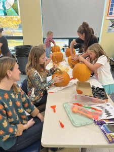 Children carving pumpkins at a table.