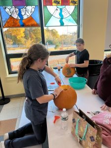 Children carving pumpkins at a table.