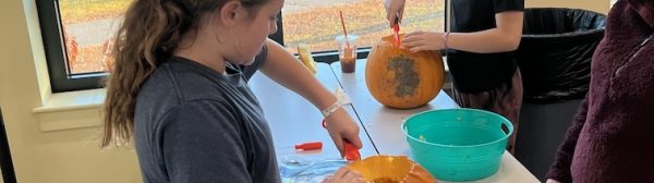 Children carving pumpkins at a table.