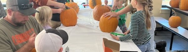 Children carving pumpkins at a table.