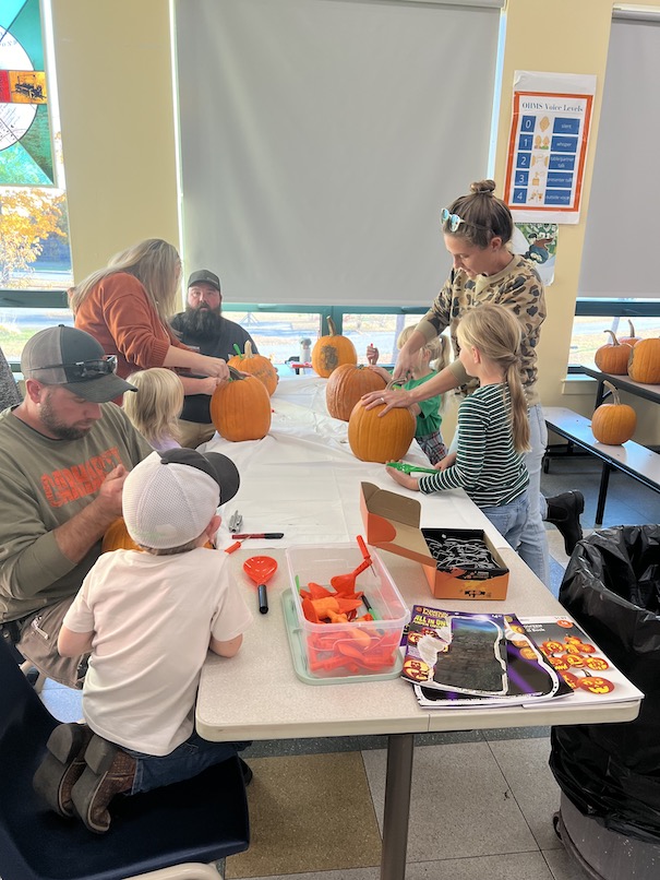 Children carving pumpkins at a table.