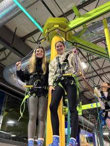 Two GLEE members wearing harnesses, standing on a platform.