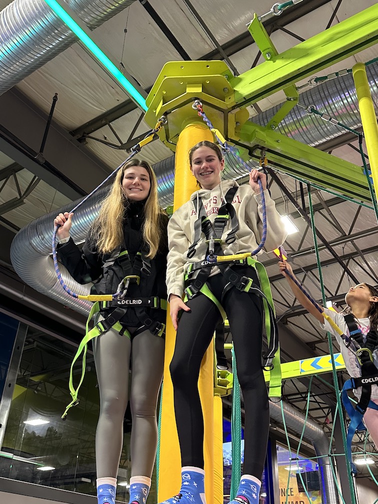 Two GLEE members wearing harnesses, standing on a platform.