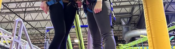 Two other GLEE members wearing harnesses, standing on a platform.