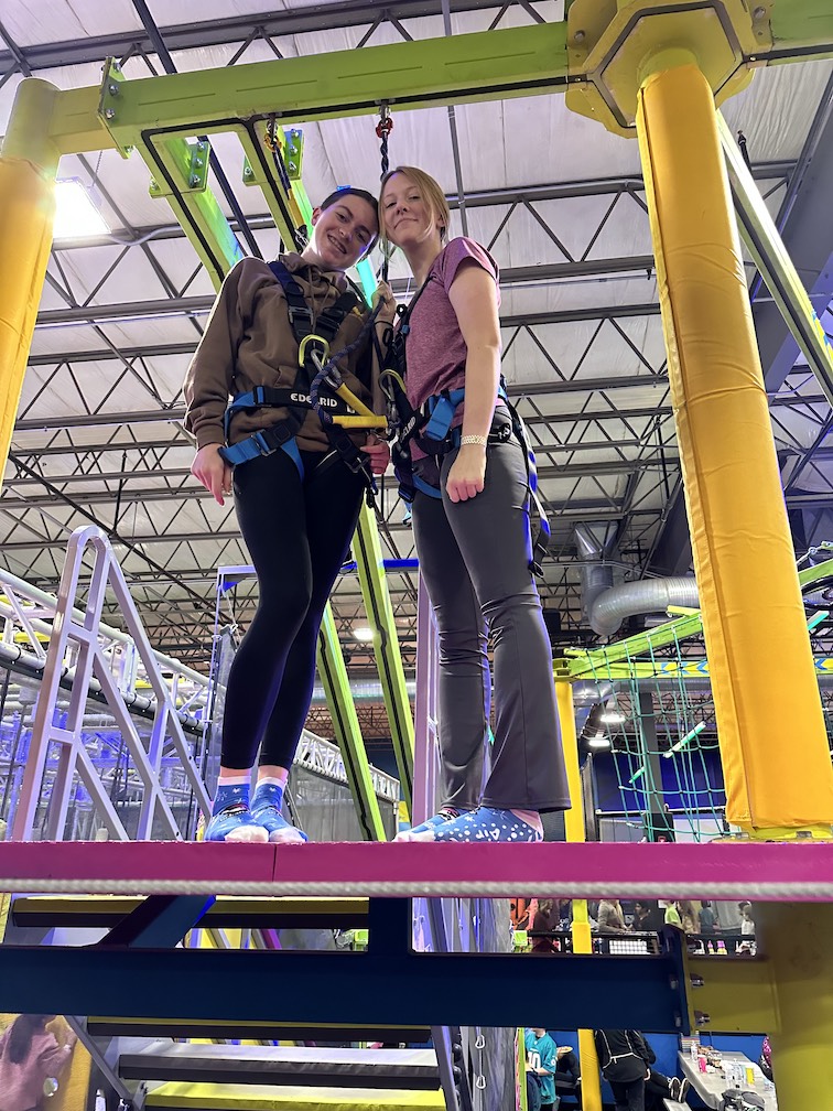 Two other GLEE members wearing harnesses, standing on a platform.