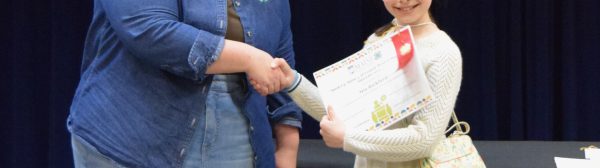 A child recieving an award from a volunteer.