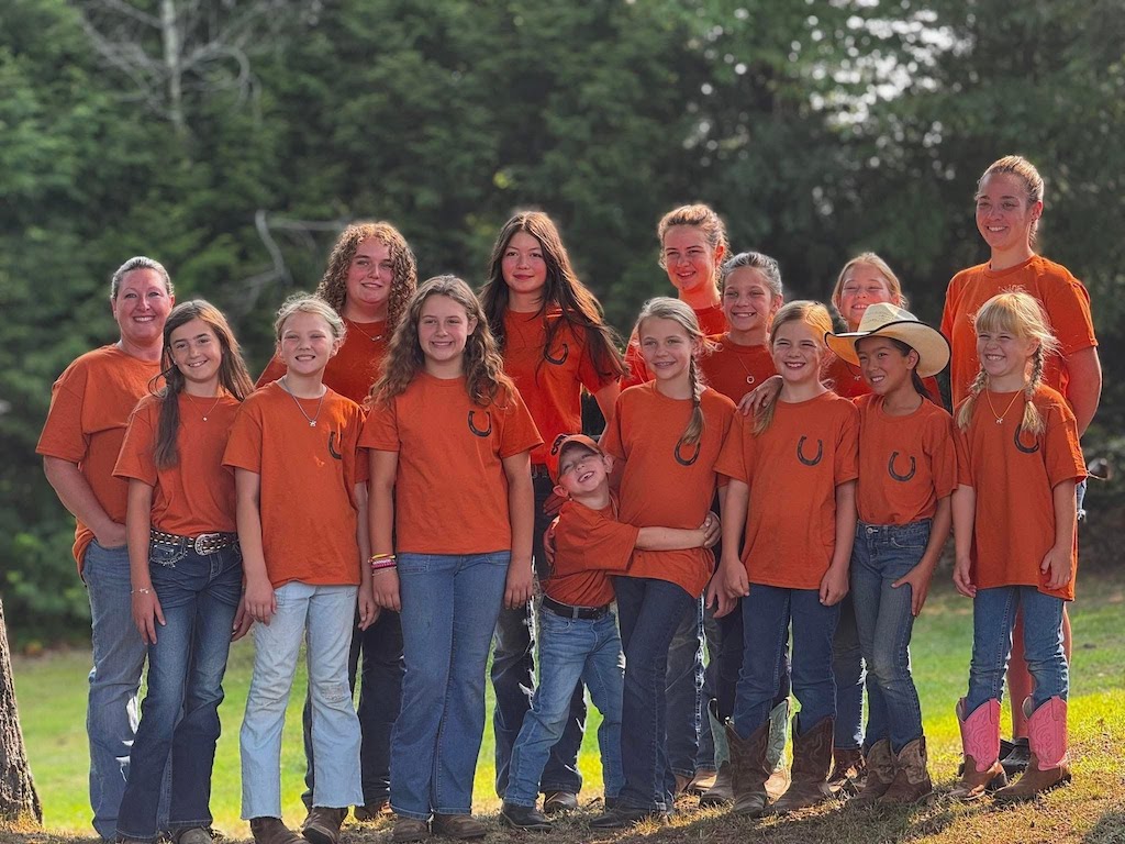 Group photo of Midcoast Mainers club members and leader. All are wearing orange horse camp shirts.