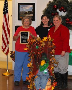 4-H leader receiving award presented by two staff